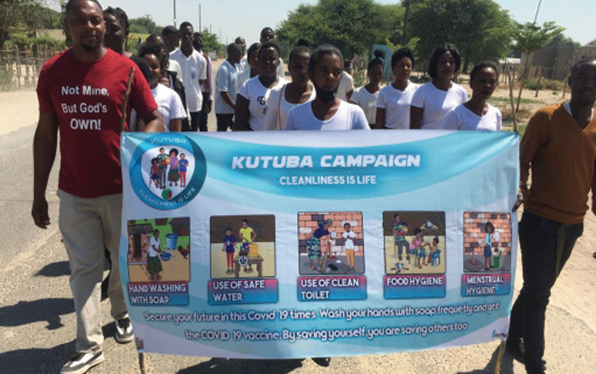Community marching with Kutuba banner