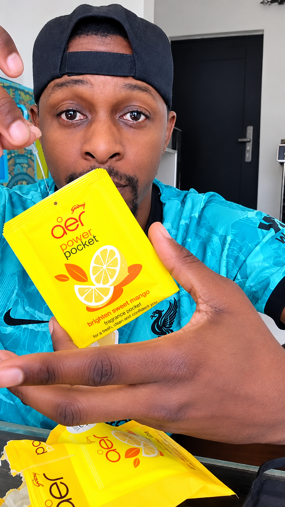 Male influencer in AER bucket hat presenting the Brighten Sweet Mango sachet