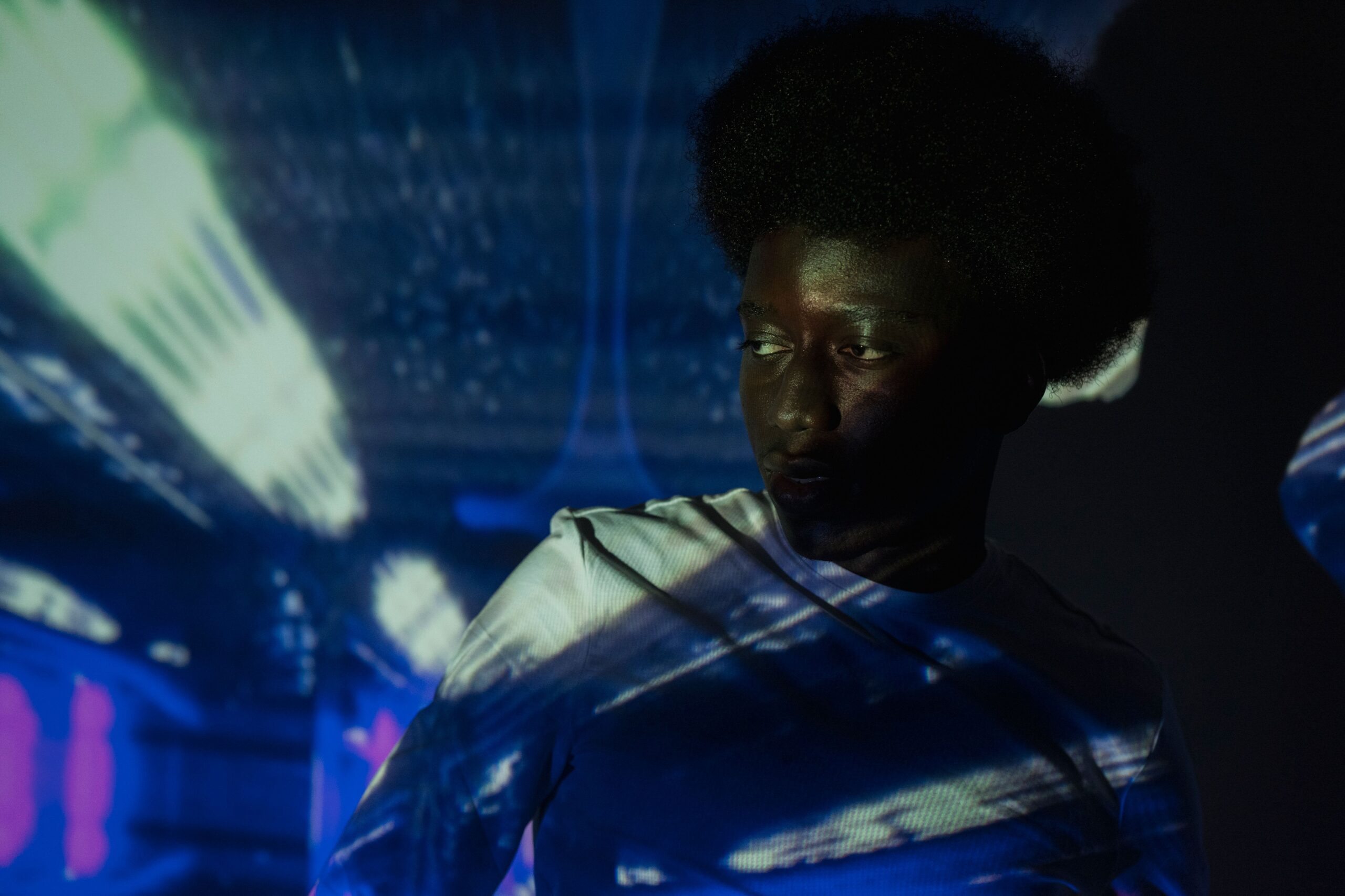Man lit by futuristic light projections in a dark studio