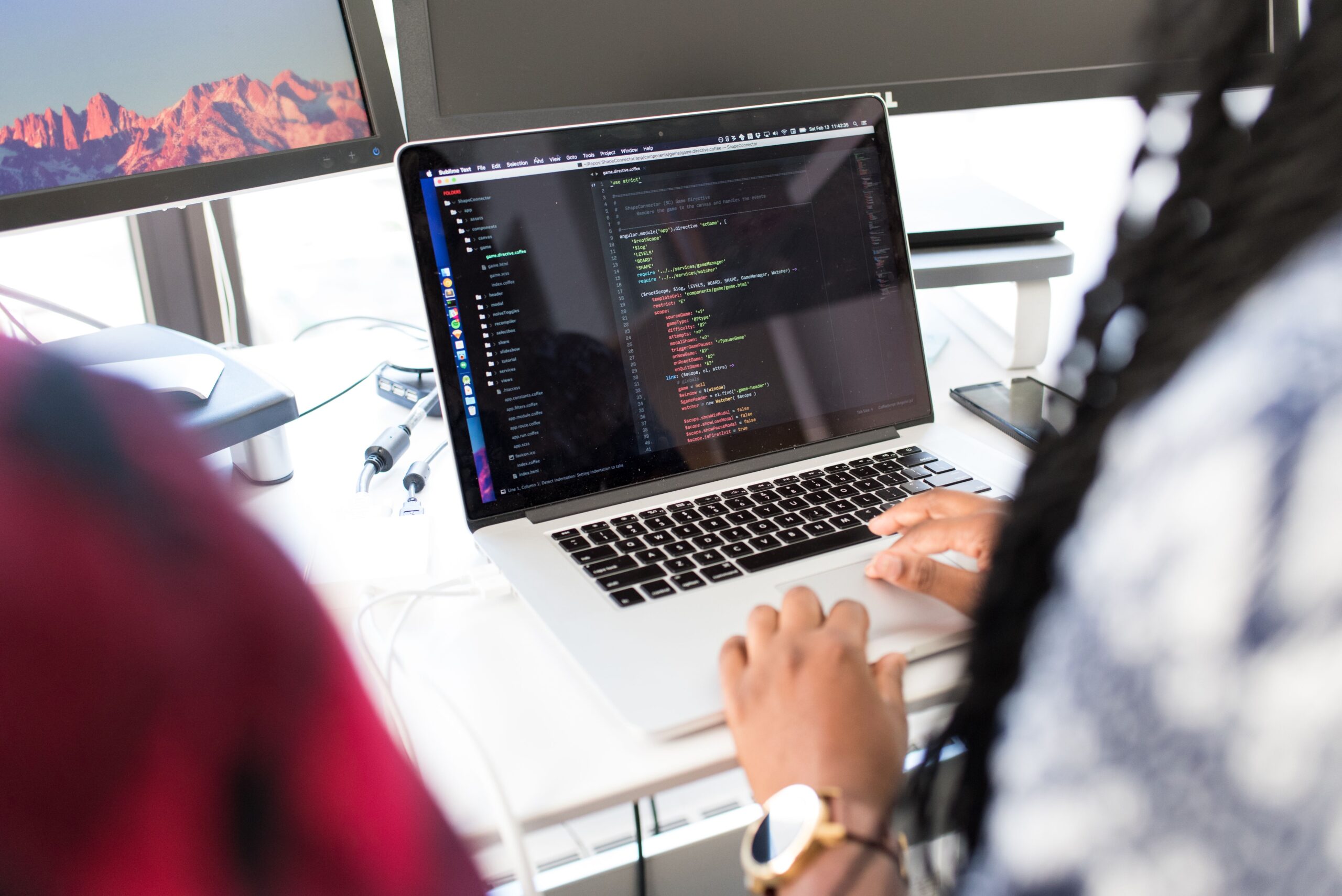 Developer writing code at a workstation with multiple monitors